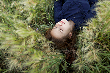 Pensive Caucasian girl laying in field