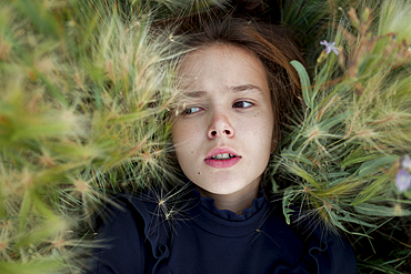 Concerned Caucasian girl laying in field