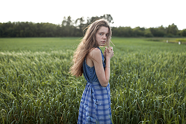 Wind blowing hair of serious Caucasian woman in field