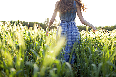 Caucasian woman walking in field of tall grass