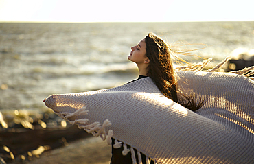 Wind blowing shawl of Caucasian woman at beach