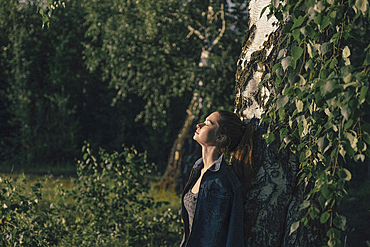 Caucasian woman leaning on tree trunk