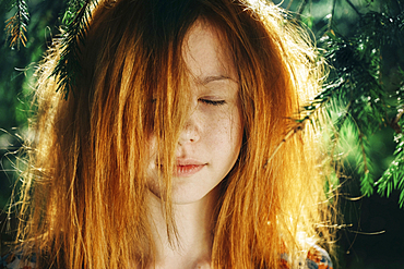 Close up of Caucasian teenage girl near pine tree