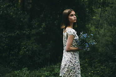 Caucasian woman holding flowers in forest