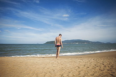 Pensive Caucasian man standing on beach