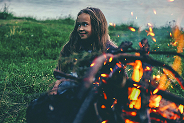 Caucasian girl sitting near campfire