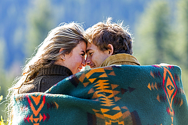 Caucasian couple wrapped in blanket rubbing noses