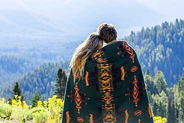 Caucasian couple wrapped in blanket admiring scenic view of landscape