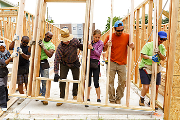 Volunteers lifting wall at construction site