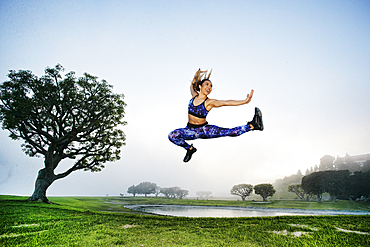 Mixed race woman exercising and jumping near lake