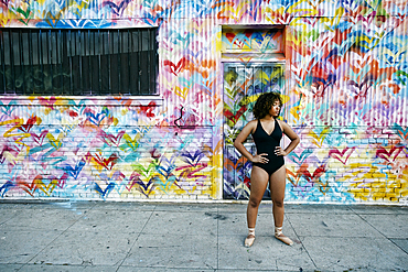 Mixed race ballet dancer resting on sidewalk