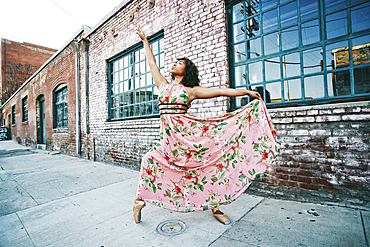 Mixed race ballet dancer wearing dress on sidewalk