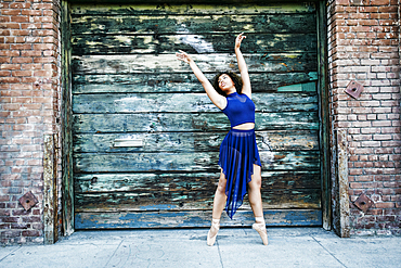 Mixed race woman dancing ballet in city