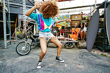 Friends watching woman spinning hoop around thighs