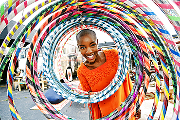 Portrait of smiling bald black woman behind hoops