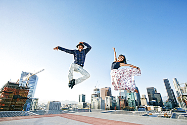 Couple dancing and jumping on urban rooftop