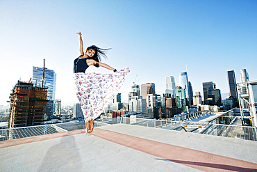 Asian woman jumping on urban rooftop