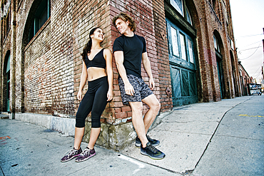 Couple leaning on corner of brick building