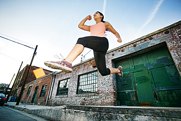 Mixed race woman jumping off loading dock