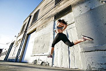 Mixed race woman running and jumping on sidewalk