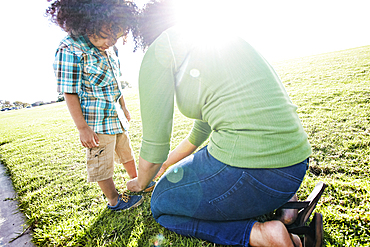 Mixed race mother tying shoe of son