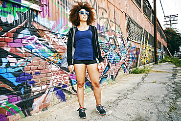 Hispanic woman standing near graffiti wall