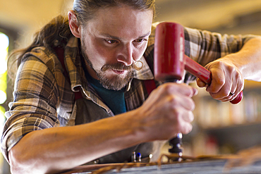 Caucasian man hammering leather