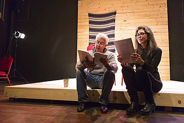 Hispanic man and woman reading scripts on theater stage