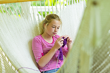 Caucasian girl laying in hammock and knitting