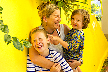 Laughing Caucasian mother hugging son and daughter