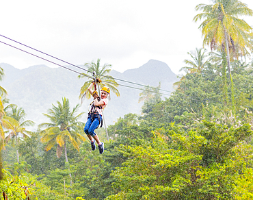 Caucasian girl hanging on zip line in forest