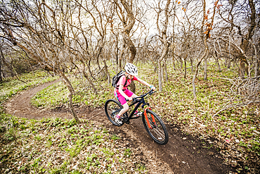 Caucasian girl riding bicycle on forest path