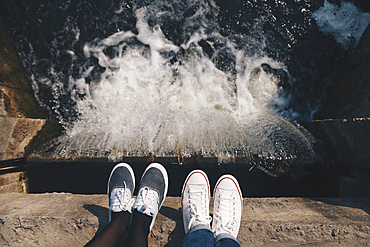 Feet of people standing at the edge of flowing water