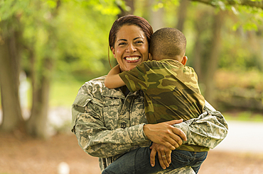 African American soldier mother carrying and hugging son