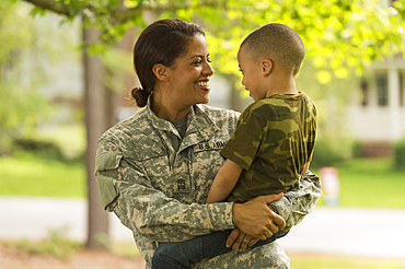 African American soldier mother carrying son