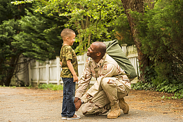 African American soldier tying shoelace for son