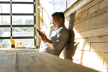 Asian man texting on cell phone in brew pub