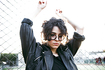 Pensive Caucasian woman leaning on chain-link fence