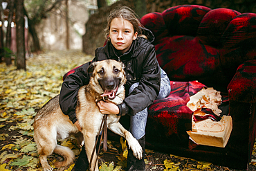 Caucasian woman sitting on sofa outdoors hugging dog