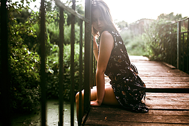 Caucasian woman sitting on wooden bridge