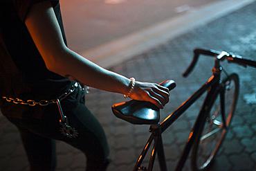 Caucasian man holding a bicycle seat at night