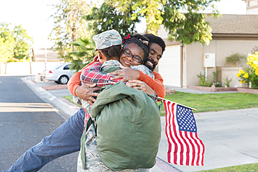 Black woman soldier hugging man and daughter