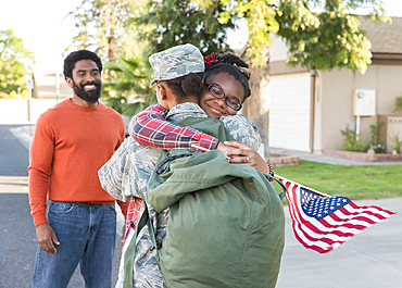 Man watching black woman soldier hugging daughter