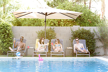 Friends relaxing with beer and cocktails at swimming pool