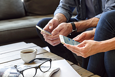 Hands of Caucasian couple texting on cell phones