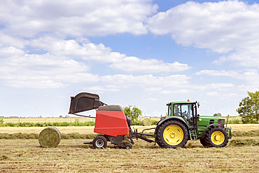 Caucasian man driving tractor baling hay