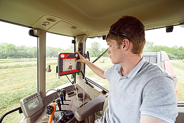 Caucasian man setting control panel in tractor on farm