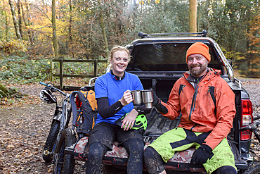 Caucasian couple toasting with coffee cups in pickup truck