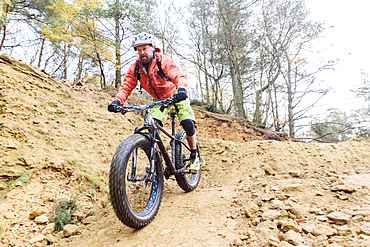 Caucasian man descending dirt trail on bicycle