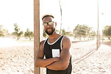 Portrait of smiling black man leaning on beach volleyball net